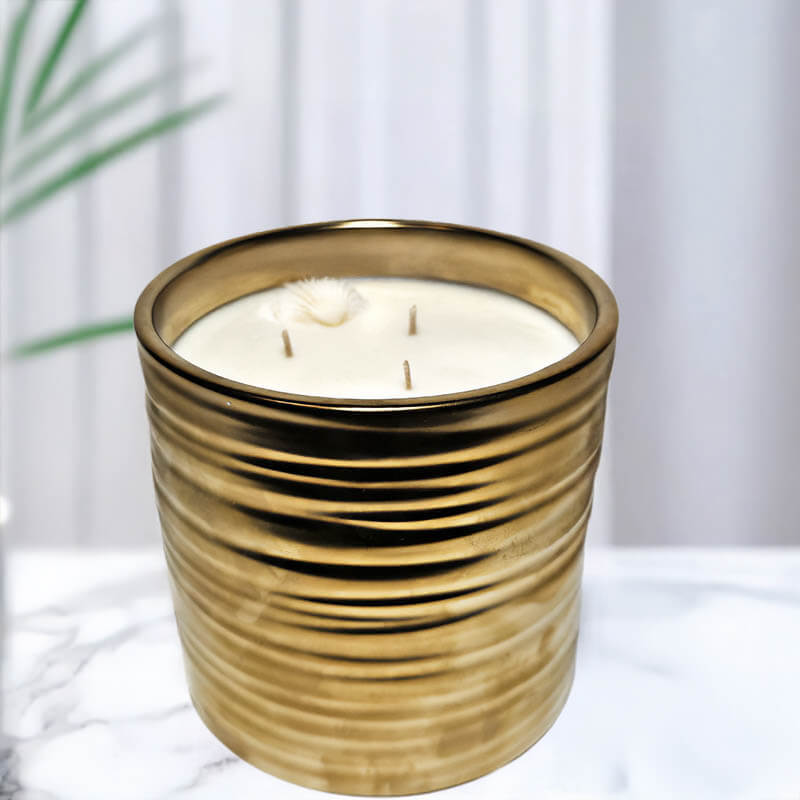 Gold textured candle holder with a white candle on a light background