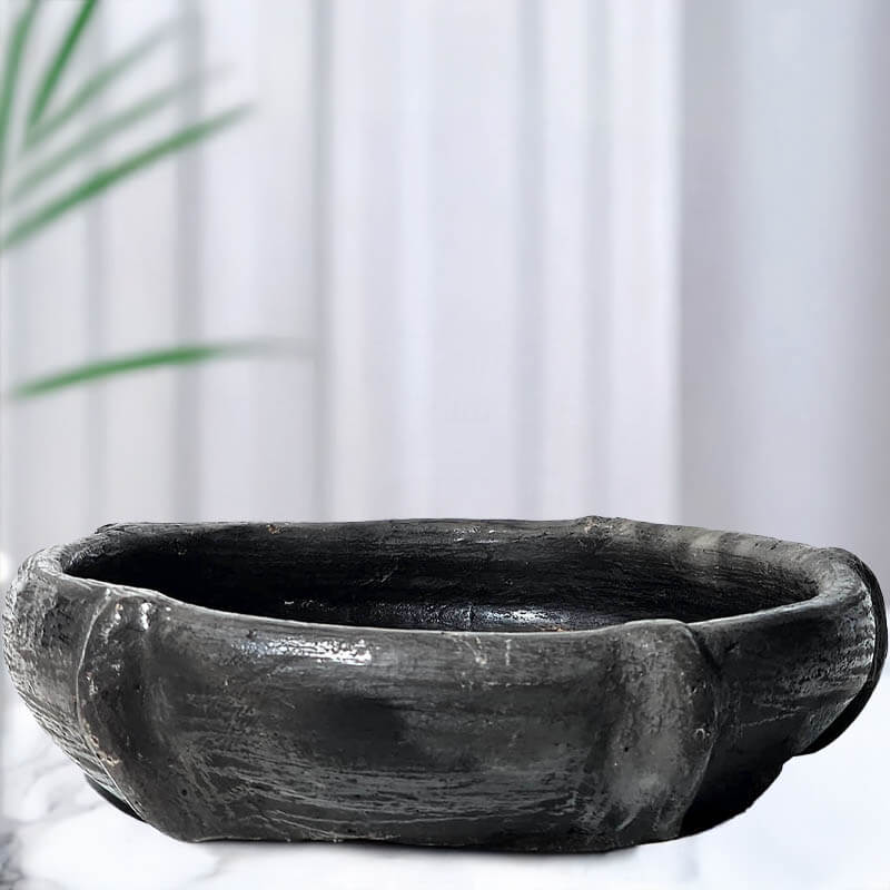Black stone large candle bowl on a white background with a plant in the corner