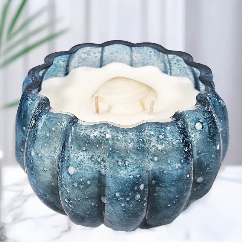 Blue glass candle bowl with a white candle inside on a light background