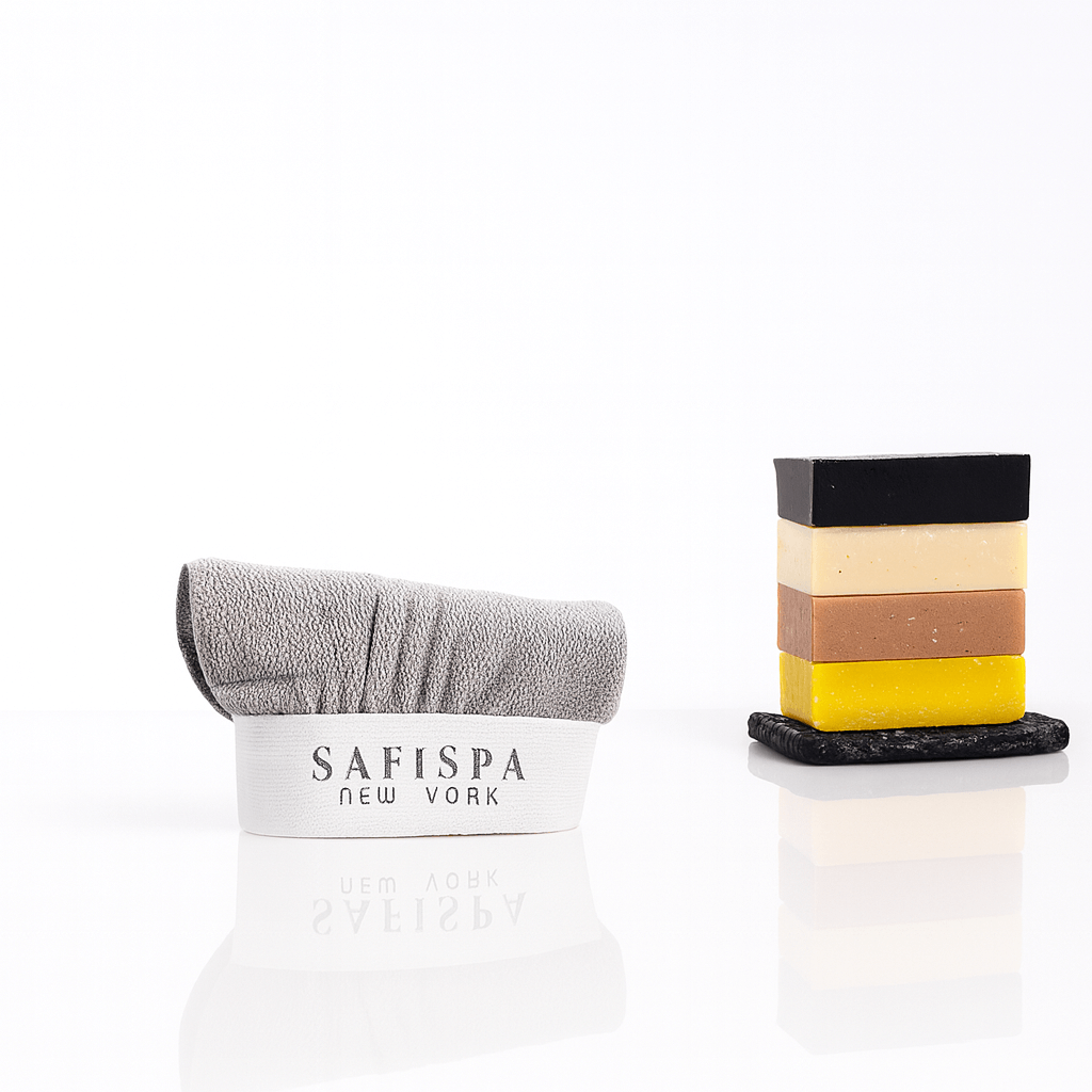 gray exfoliating towel with logo and stacked handmade artisanal soaps on a glossy white background, perfect for spa and skincare routines.