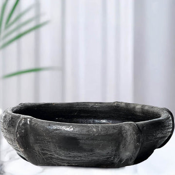 Black stone large candle bowl on a white background with a plant in the corner