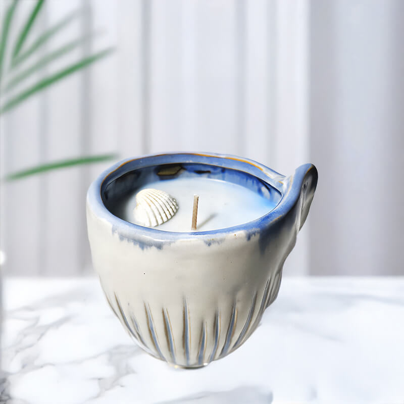 Ceramic candle holder with a candle inside on a white surface with a blurred background