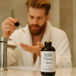 Man applying beard oil with a bottle of SAFISPA Nourishing Beard Oil Tobacco + Spice