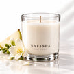 SaFiSpa Freesia & Pear scented soy candle in a clear glass vessel with freesia flowers and fresh pear on a white background