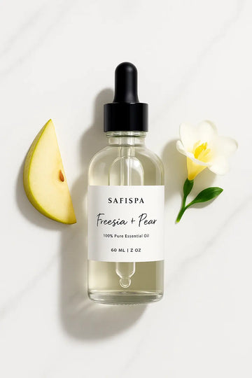 top view of SaFiSpa Freesia + Pear Essential Oil bottle on marble background with natural botanicals