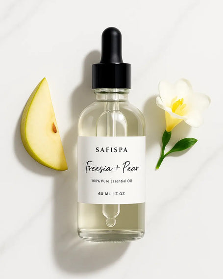 top view of SaFiSpa Freesia + Pear Essential Oil bottle on marble background with natural botanicals