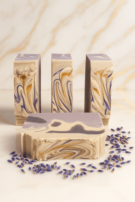 Luxury handcrafted Lavender Vanilla artisan soap bars with purple, gold, and cream swirls, made with natural moisturizing ingredients for soft, healthy skin, displayed on a white marble surface with scattered lavender buds.