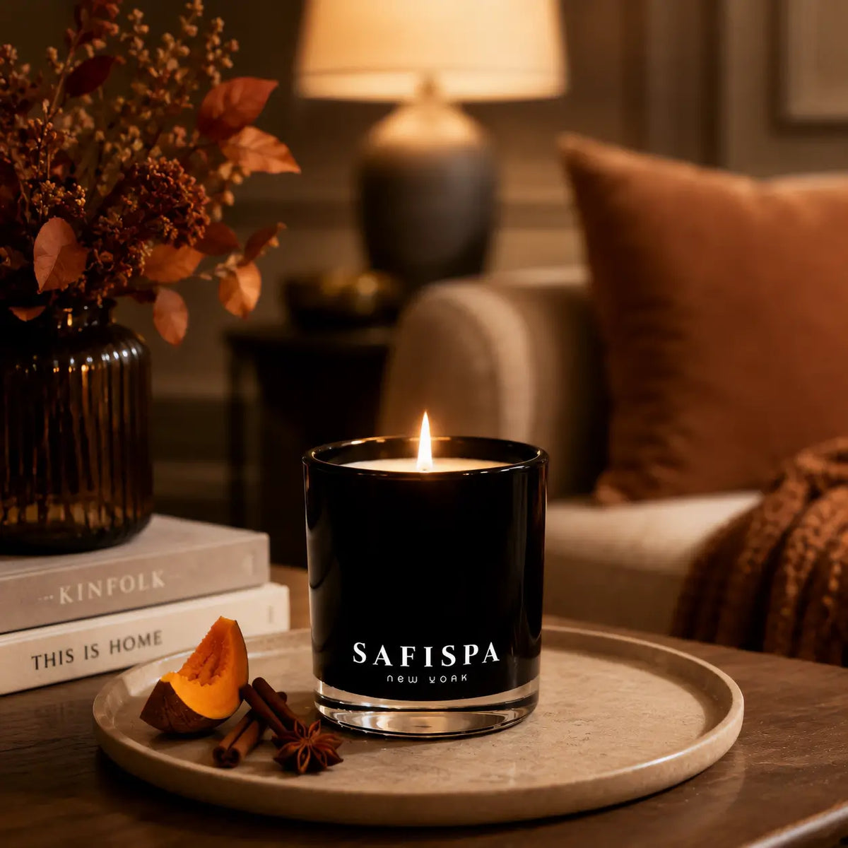 Lit SaFiSpa Pumpkin Spice scented candle in a warm luxury fall home setting