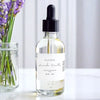 Bottle of Safispa Lavender Vanilla essential oil with a dropper next to a vase of lavender flowers.