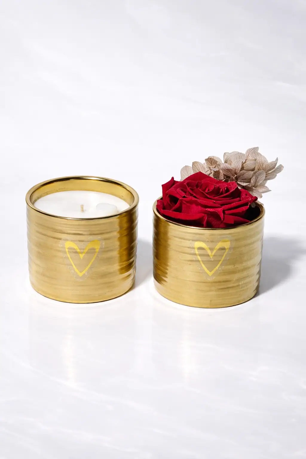 Two gold containers with a candle and red roses on a white background