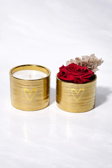 Two gold containers with a candle and red roses on a white background