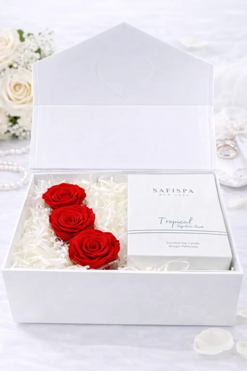 White box with red roses and a product inside, surrounded by white flowers.