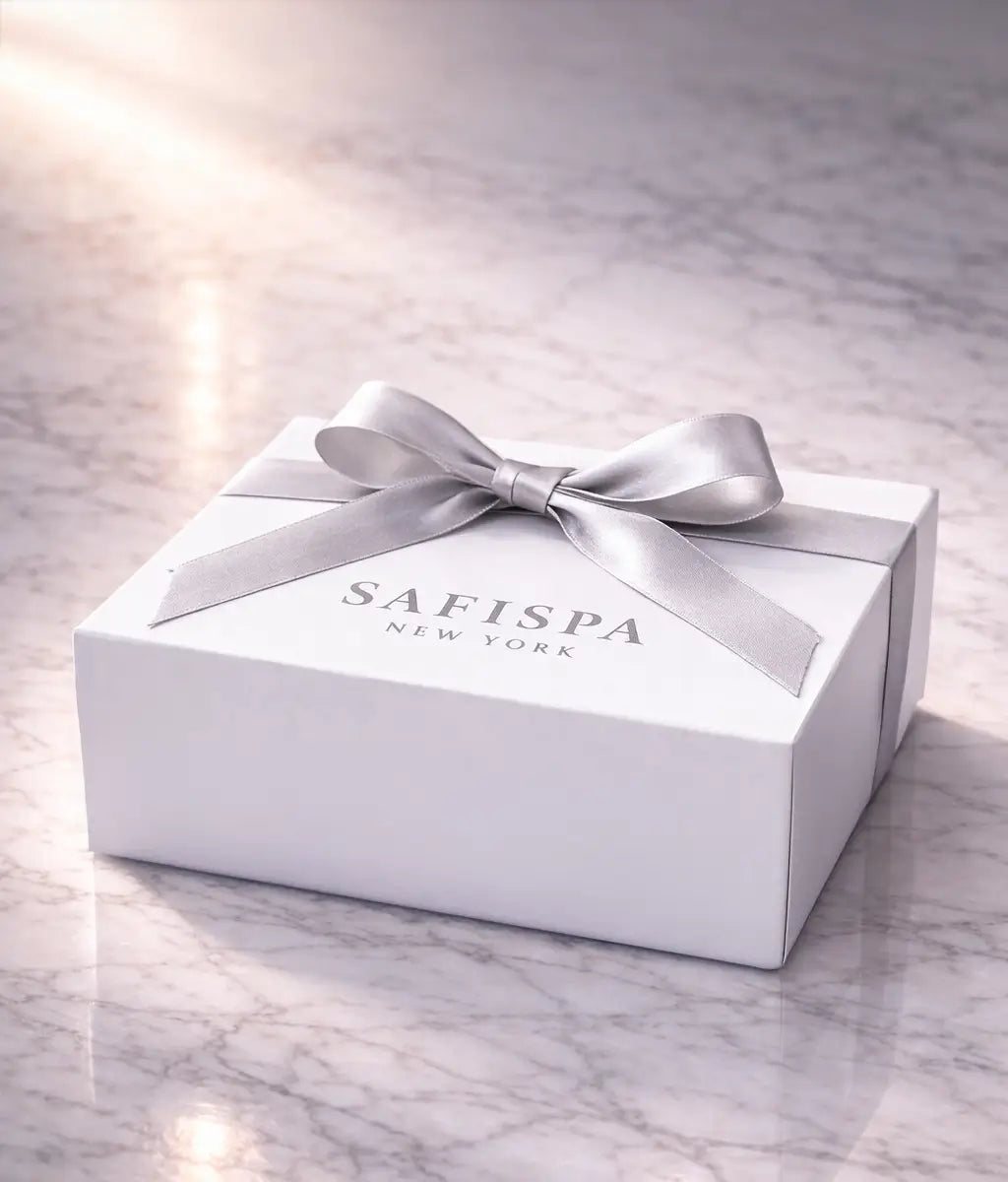 White gift box with a silver ribbon on a marble surface, featuring the brand 'SAFISPA New York'.