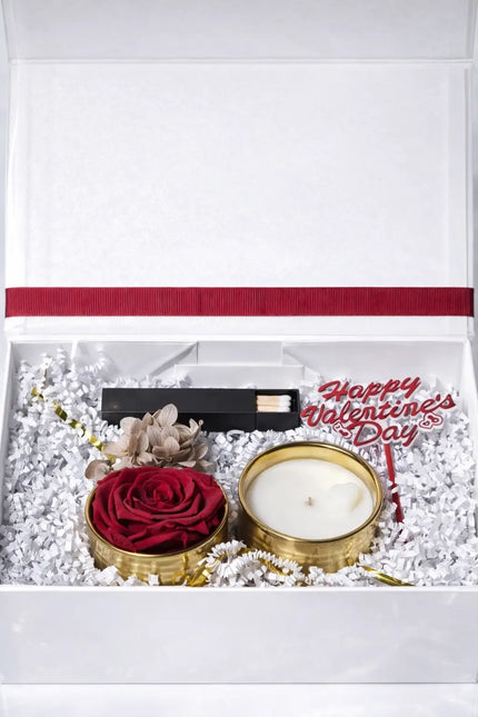 Valentine's Day gift set with a candle, rose, and decorative card in a white box.