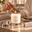 Woman lighting a SaFiSpa Vanilla Essence scented candle in an elegant home setting for a warm home fragrance ritual.