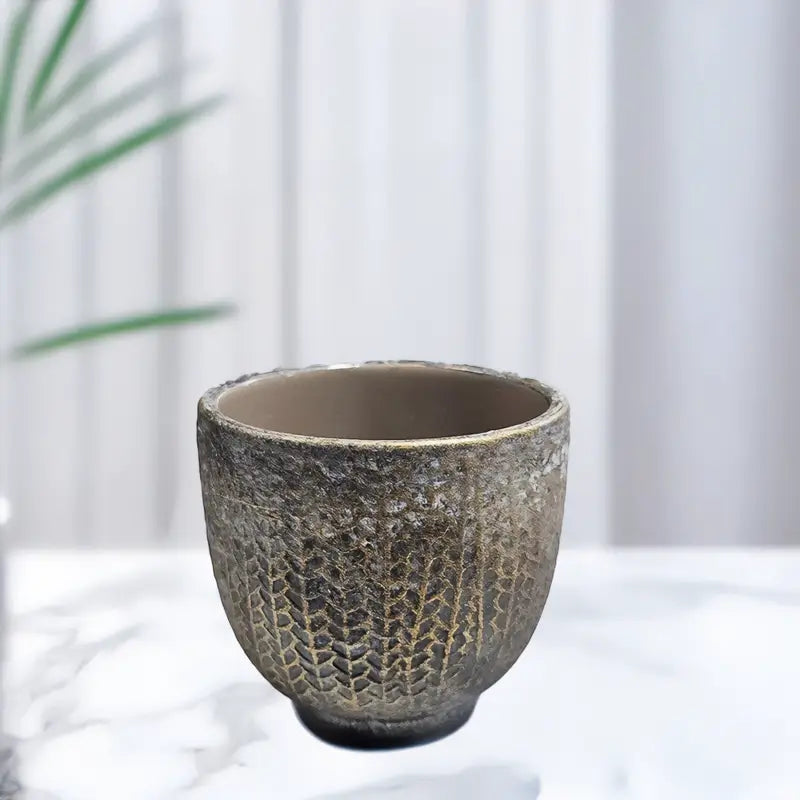 Textured ceramic cup on a white surface with a blurred background