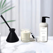 Luxury Fragrance gift lavender vanilla candle, diffuser, and bottle on a light surface with a white curtain background