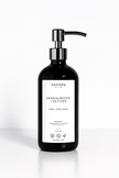 Sandalwood + Vetiver Hand and Body Moisturizing Body Wash in black pump bottles with stainless steel tops, set against a golden marble background for an elegant presentation.
